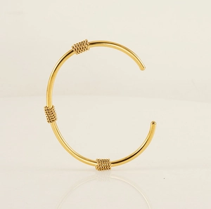 Detailed view of gold stainless steel cuff bracelet with braided knot textured accents