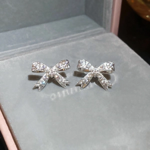 Gros plan de boucles d'oreilles nœud en argent pavées de zircons sur un plateau