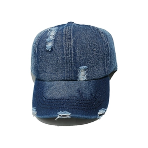 Washed distressed denim baseball cap with vintage frayed holes and retro street style
