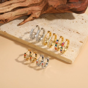 Detail view of gold and silver hoop earrings with rectangular cubic zirconia on stone