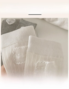 Detail of high-elasticity ribbed cuffs with delicate lace heart patches on mid-tube socks