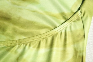 Gros plan sur le motif floral tie-dye vert et les détails de couture à double aiguille