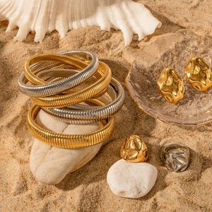 18K gold and silver ribbed open bracelets with vintage emerald zircon on beach sand