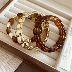 Detail of amber and gold resin chunky bracelets in a beige velvet jewelry box