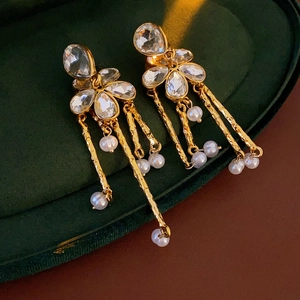 Macro shot of vintage gold flower earrings with crystals and pearl tassels on green velvet