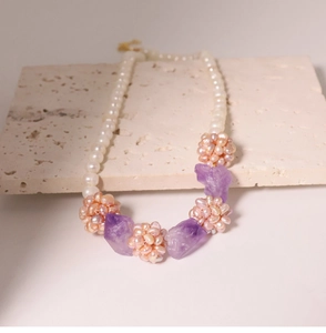 Detail view of freshwater pearl necklace with amethyst stones on a textured stone surface