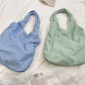 Close-up of textured bubble fabric on blue and green large capacity canvas tote bags