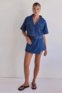 Detail of dark blue denim utility set featuring a short-sleeve shirt and wrap skirt