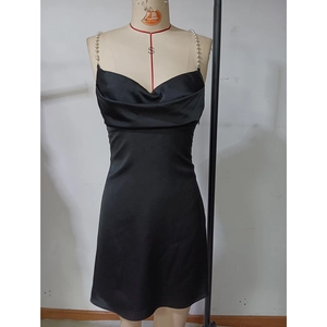 Détail du col bénitier sur robe mini robe en satin noir avec bretelles élégantes en perles