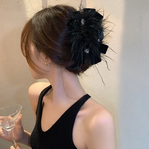 Détail d'une élégante pince à cheveux en velours noir avec plumes et strass sur un modèle