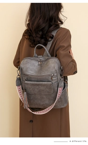 Gray vintage faux leather backpack featuring a colorful woven strap and tassel detail