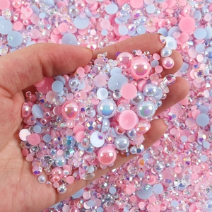 Close-up of hand holding mixed pastel resin pearls and rhinestones for DIY nail art