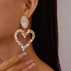 Detailed close-up of luxurious heart-shaped gold earrings with sparkling pavé rhinestones