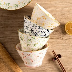 Set of four Japanese style ceramic bowls with floral patterns and gold rim on wood table