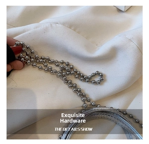 Close-up of shiny silver beads chain and textured handle of the stylish handbag