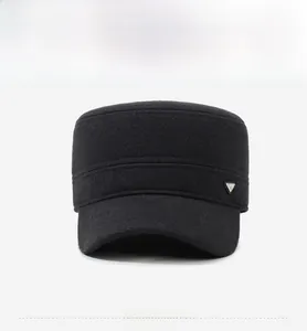 Detail of black winter flat cap featuring thick fabric texture and a metal triangle logo