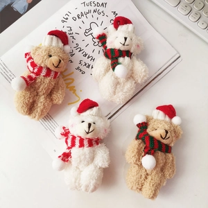 Close-up of plush Christmas bears with Santa hats and striped scarves on a white desk