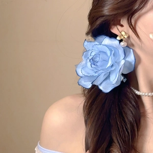 Detail of blue fabric flower hair clip worn on a side braid for a romantic look
