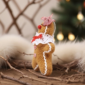 Plush gingerbread man Christmas ornament with lace trim and red bow on cozy background
