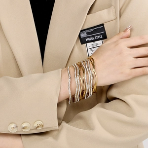 Elegant gold titanium steel wave bangles with pavé rhinestones in a layered set style