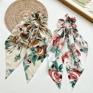 Detailed view of floral fabric scrunchies with long streamers in beige and white