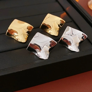 Gros plan de boucles d'oreilles carrées torsadées plaquées or et argent sur plateau noir