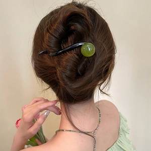 Minimalist black wavy hair stick with a green jade-like bead shown on an elegant bun