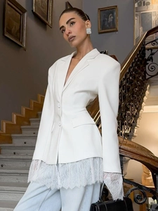 Detailed close-up of white blazer hem featuring elegant lace patchwork and premium stitching