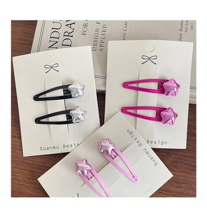 Close-up of star-shaped metallic snap hair clips in black and pink on display card