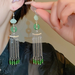 Detail of Chinese style earrings featuring emerald green beads and silver metal tassels