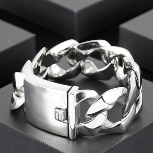 Polished stainless steel Cuban chain bracelet for men with a square clasp on a black pedestal