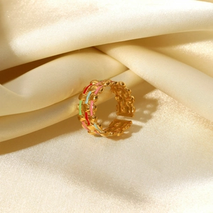 Macro detail of 18K gold-plated ring with colorful enamel stripes on premium silk