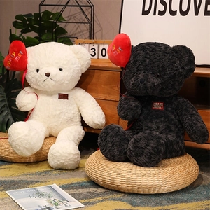 Close-up of black and white plush teddy bears holding red hearts in a cozy home setting