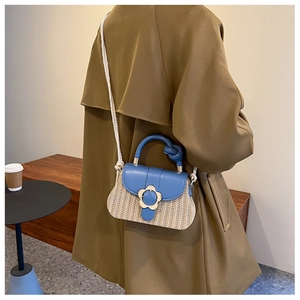 Détail du rabat en cuir bleu et base en paille tressée avec boucle fleurie dorée du sac