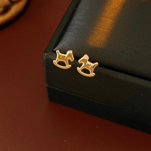 Détail macro de boucles d'oreilles cheval à bascule dorées sur boîte en cuir de luxe