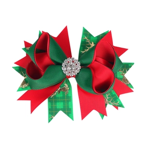Detailed view of Christmas bow hair clip with red-green ribbons and glittery elk patterns
