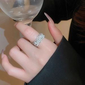 Detail of elegant layered pearl and zircon ring worn while holding a crystal glass