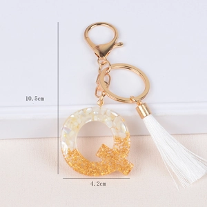 Detail shot of resin letter Q keychain with gold flakes, tassel, and size dimensions