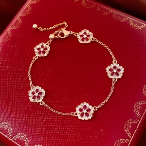 Detailed macro view of 18k gold flower bracelet with red and white gemstones