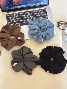 Detail of four fabric scrunchies with 'Hand Made' labels on a desk with laptop