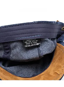 Close-up of washed denim beret interior showing stitching details and 100% cotton care label