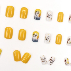 Short square press-on nails with yellow floral patterns and 'Like More' script
