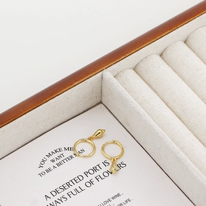 Close-up of gold seashell hoop earrings with white zircon inlay on display card