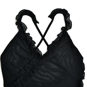 Detail of black mesh dress featuring elegant ruffle trim and thin crisscross back straps
