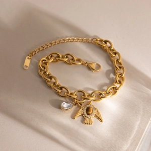 Detail eines 18K vergoldeten Armbands mit Tigerauge-Vogelanhänger und Wassertropfenkristall