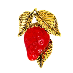 Vibrant red enamel strawberry brooch with antique gold leaf detail on white background