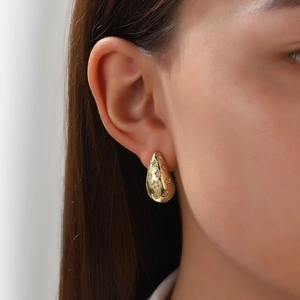 Macro detail of gold-plated teardrop earrings with star cutouts and sparkling cubic zirconia