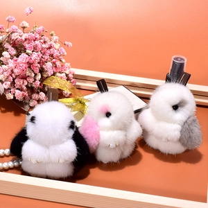 Plush mink fur rabbit charms in three colors on a stylish warm orange background