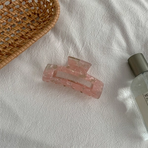 Pink marble texture acrylic hair claw clip with rectangular cutout on white fabric