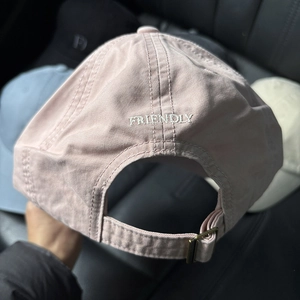 Detail of soft pink cotton baseball cap with FRIENDLY embroidery and metal buckle